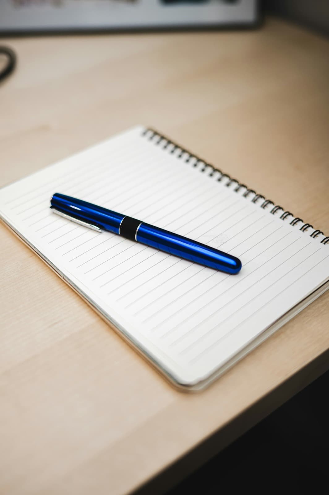 A pen resting on an open notebook on a desk